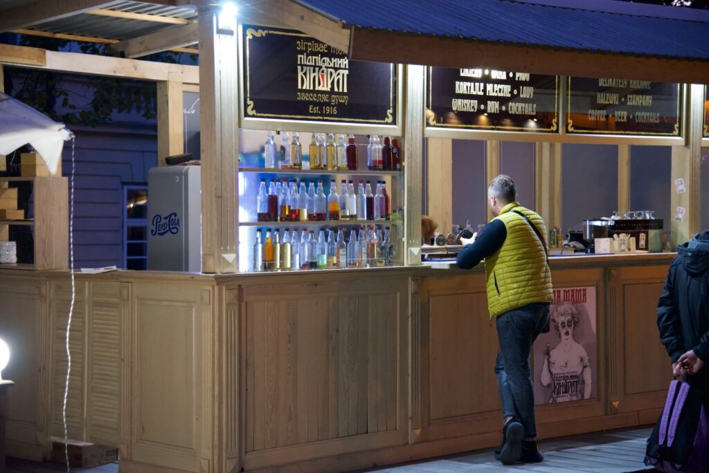 Lwów nocą - imprezy i alkohol blog podróżniczy, mężczyzna przy kiosku z alkoholem na lwowskim rynku
